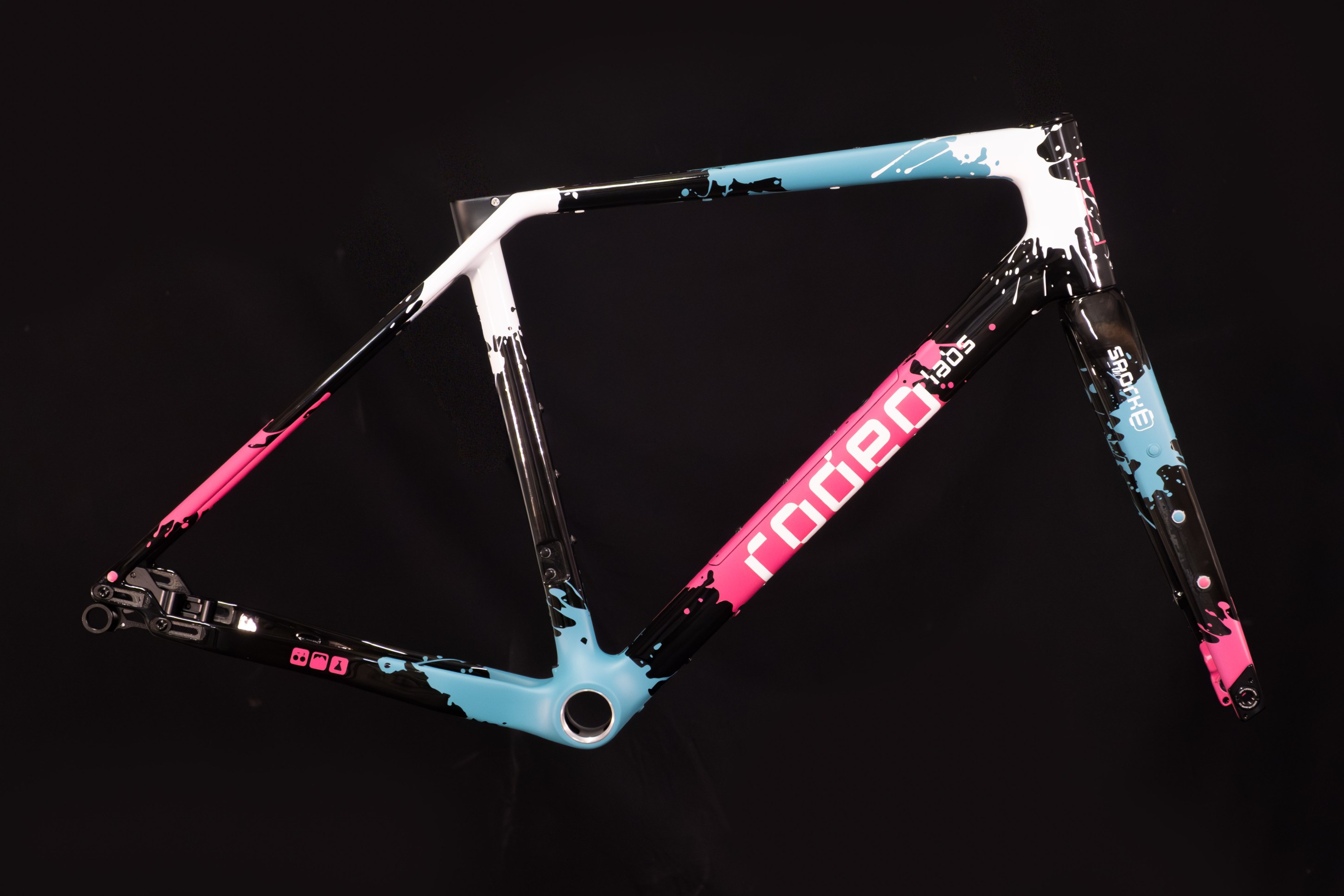 A colorful bicycle frame featuring a dynamic paint splash design with pink, blue, and black colors.