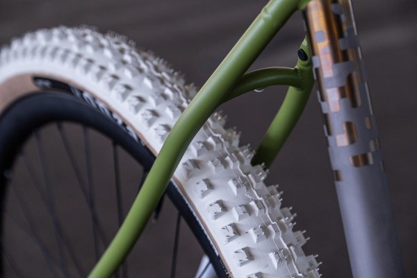 Close-up of a bicycle frame with a green color and a white, textured tire, showcasing the intricate tread pattern.