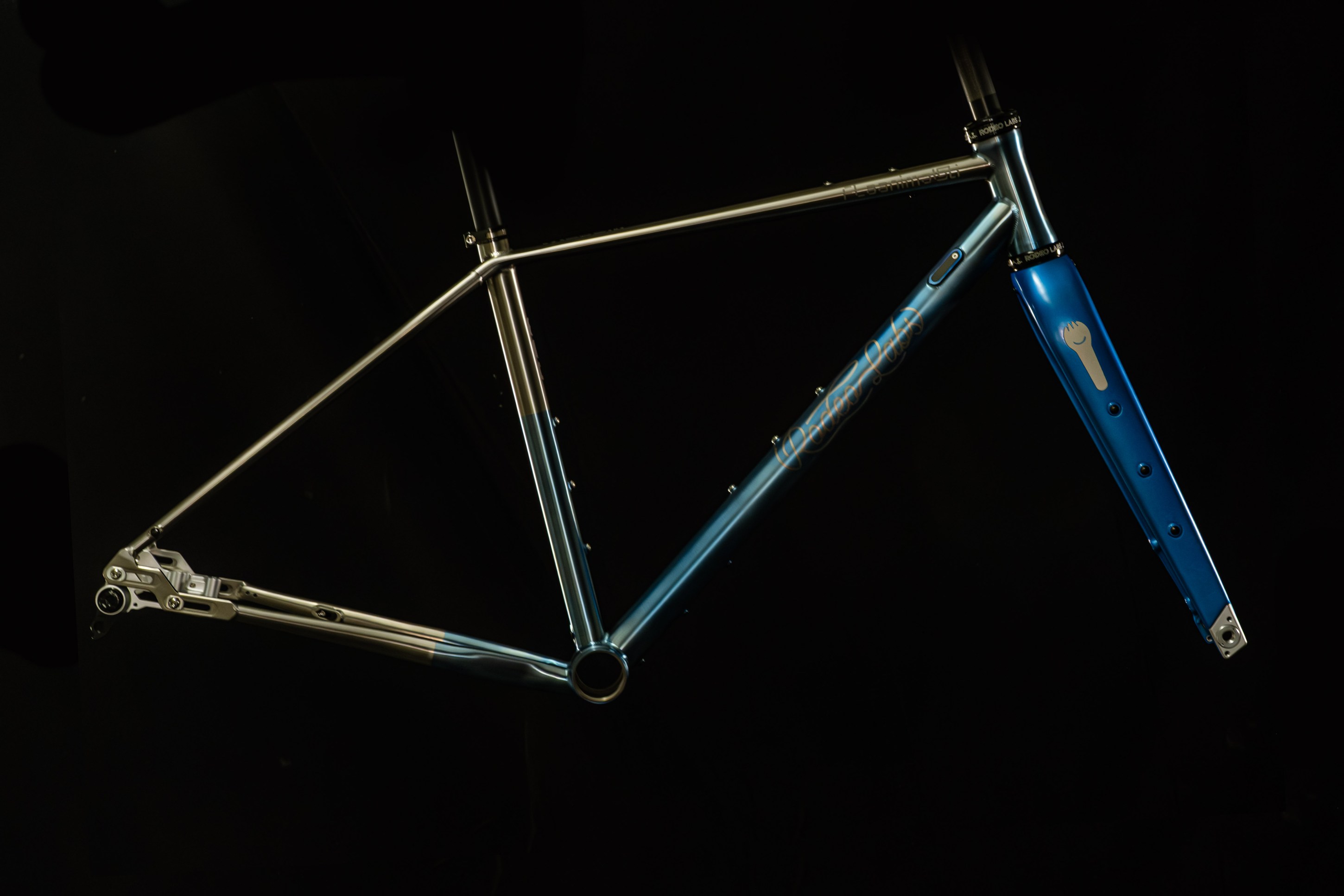 A close-up view of a bicycle frame showcasing a sleek design with a gradient blue finish, featuring a distinctive fork and various mounting points.