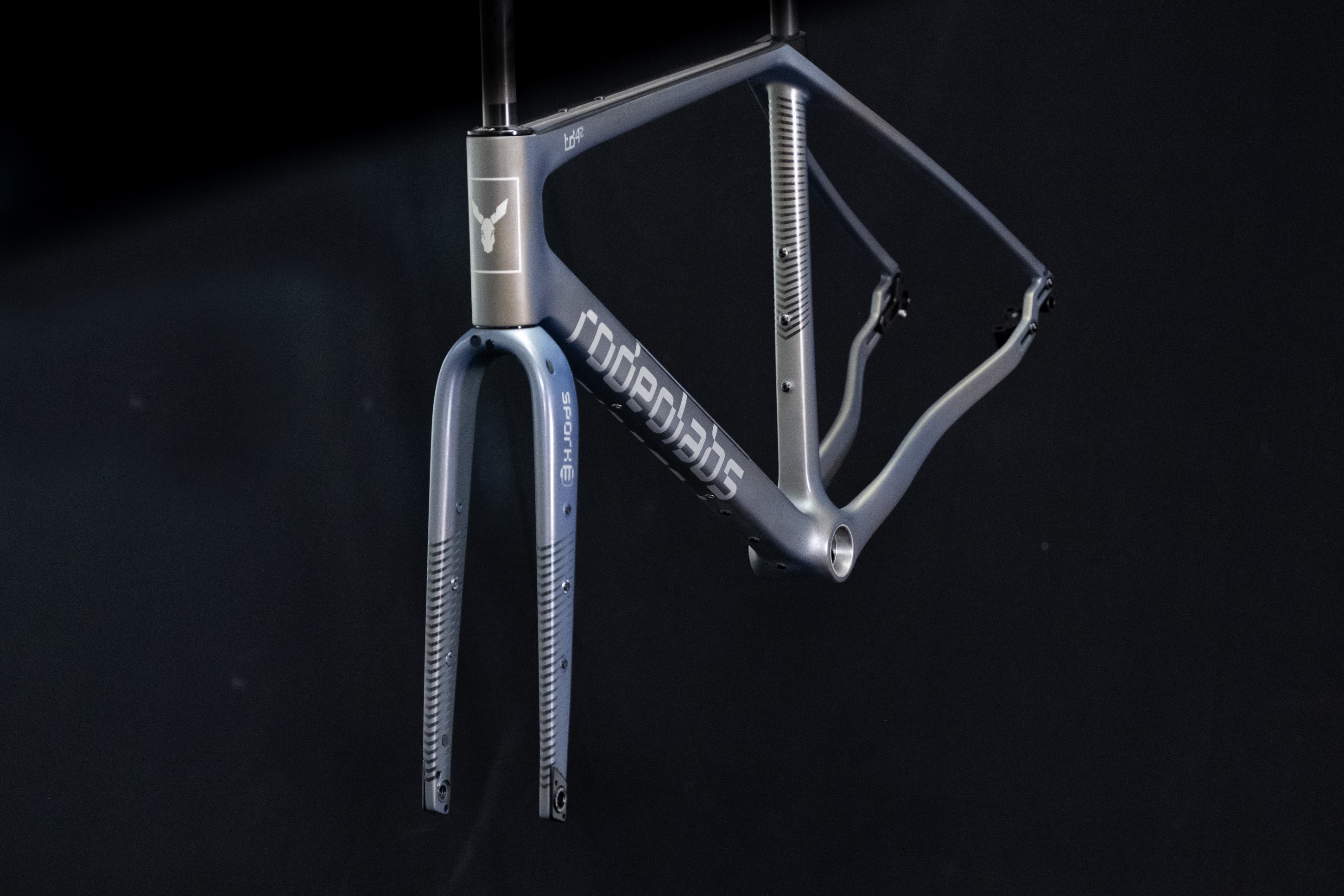 Close-up of a lightweight bicycle frame with a unique geometric design and fork, showcased against a dark background.