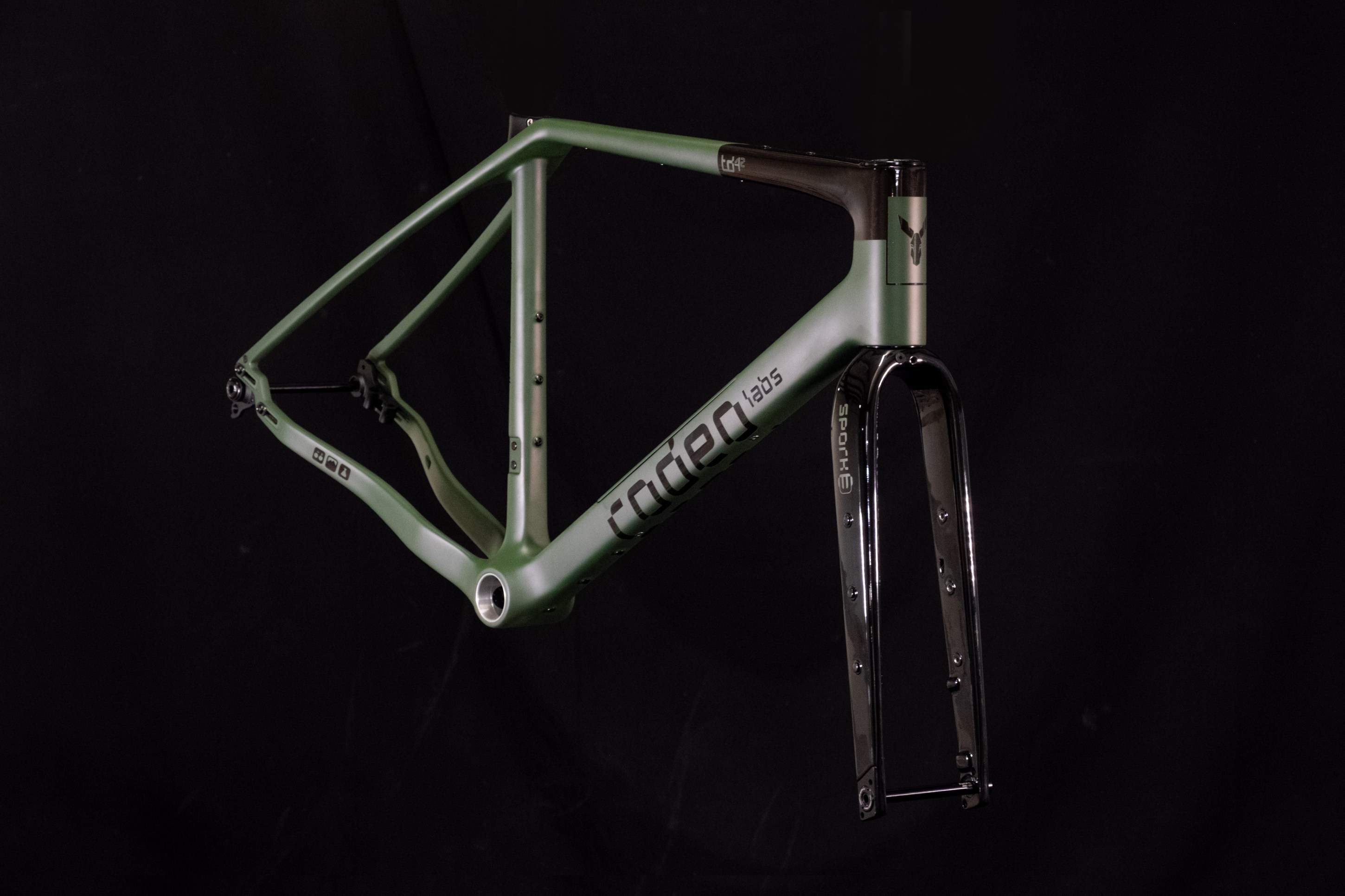 A green bicycle frame with a black fork displayed against a dark background.