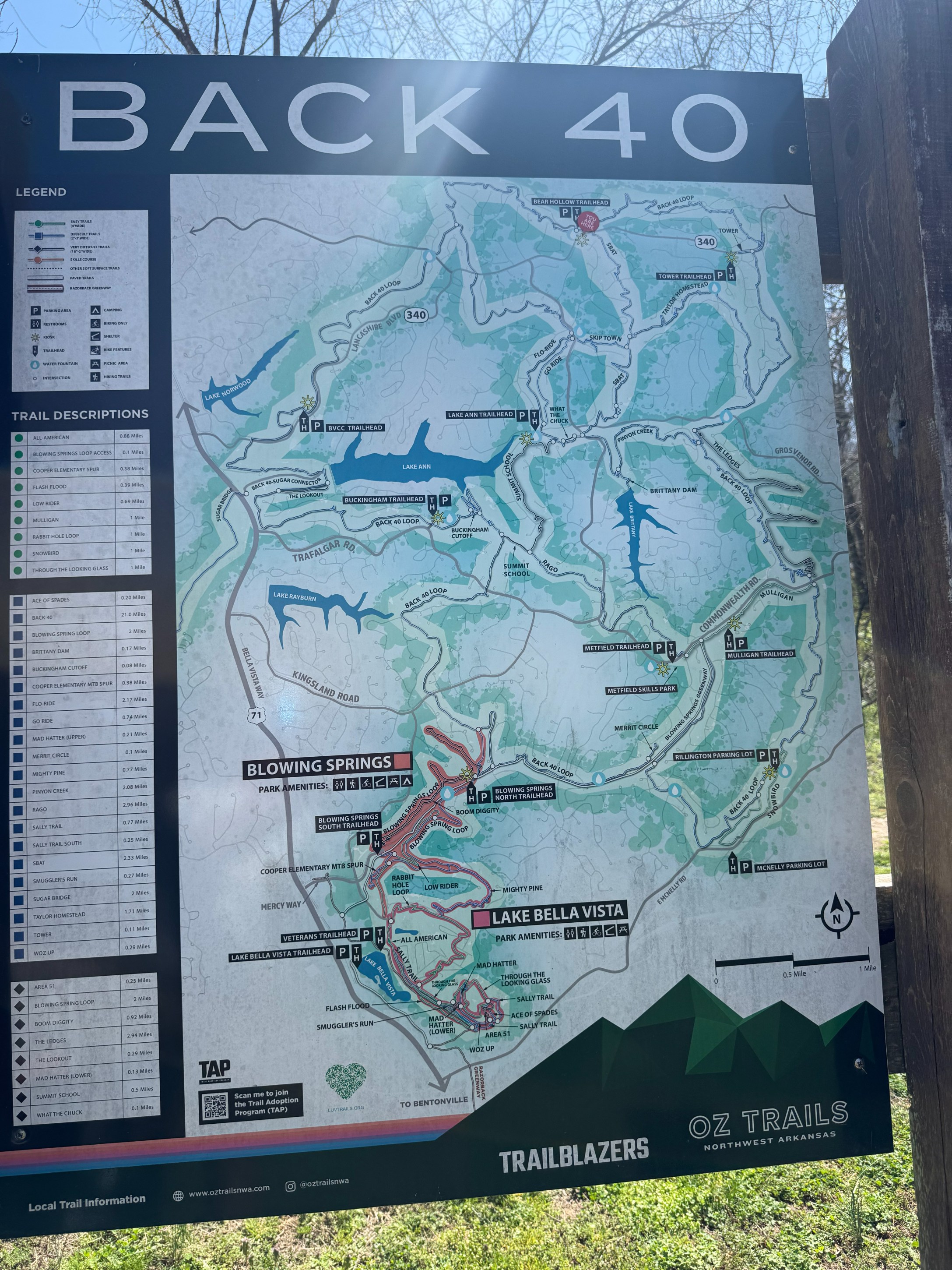 A detailed trail map of the Back 40 area, highlighting various trails, parks, and amenities, including landmarks such as Blowing Springs and Lake Bella Vista. Includes a legend for trail descriptions and distances.