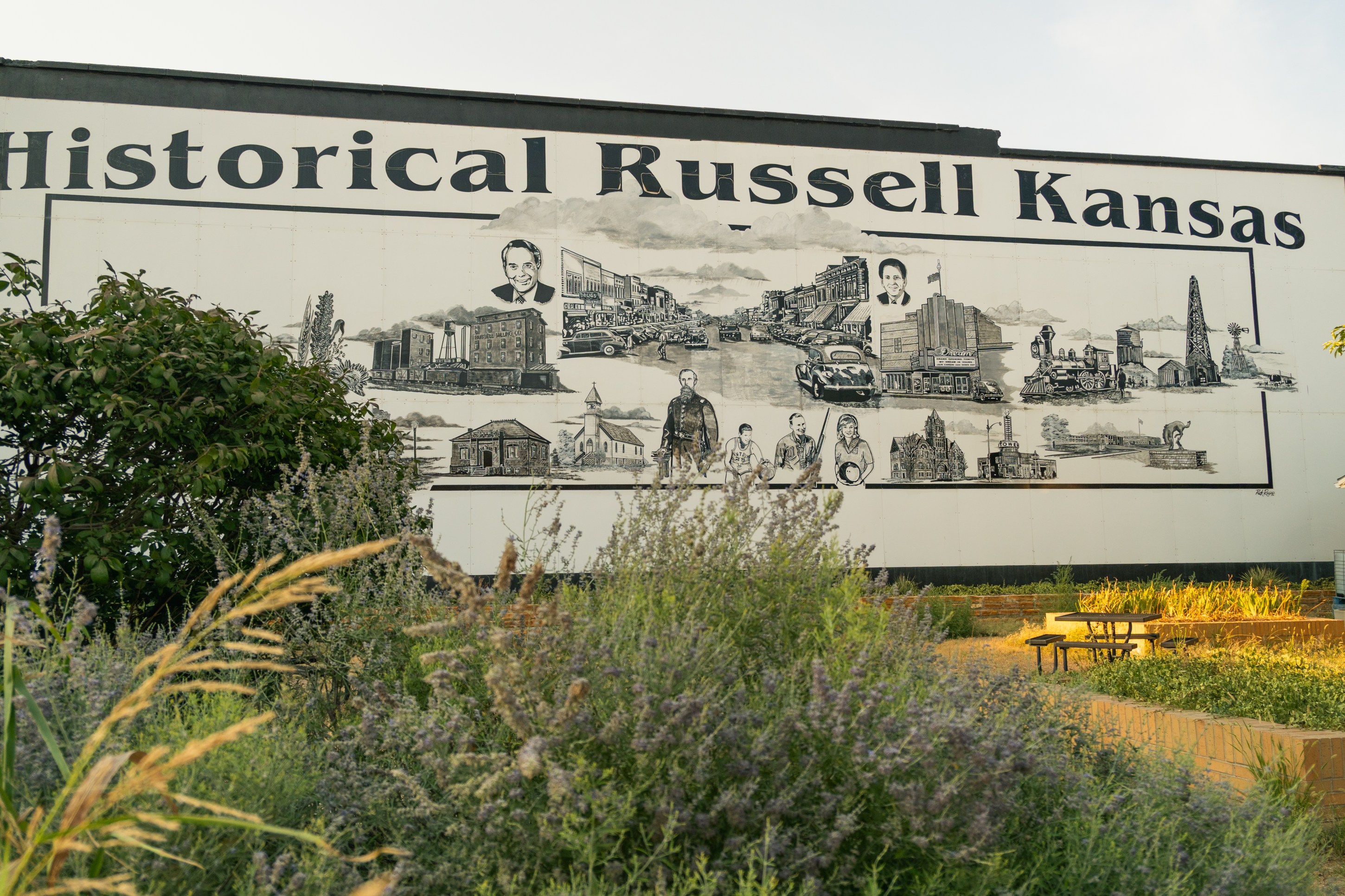 A mural depicting historical scenes and figures from Russell, Kansas, with the text 'Historical Russell Kansas' prominently displayed at the top.