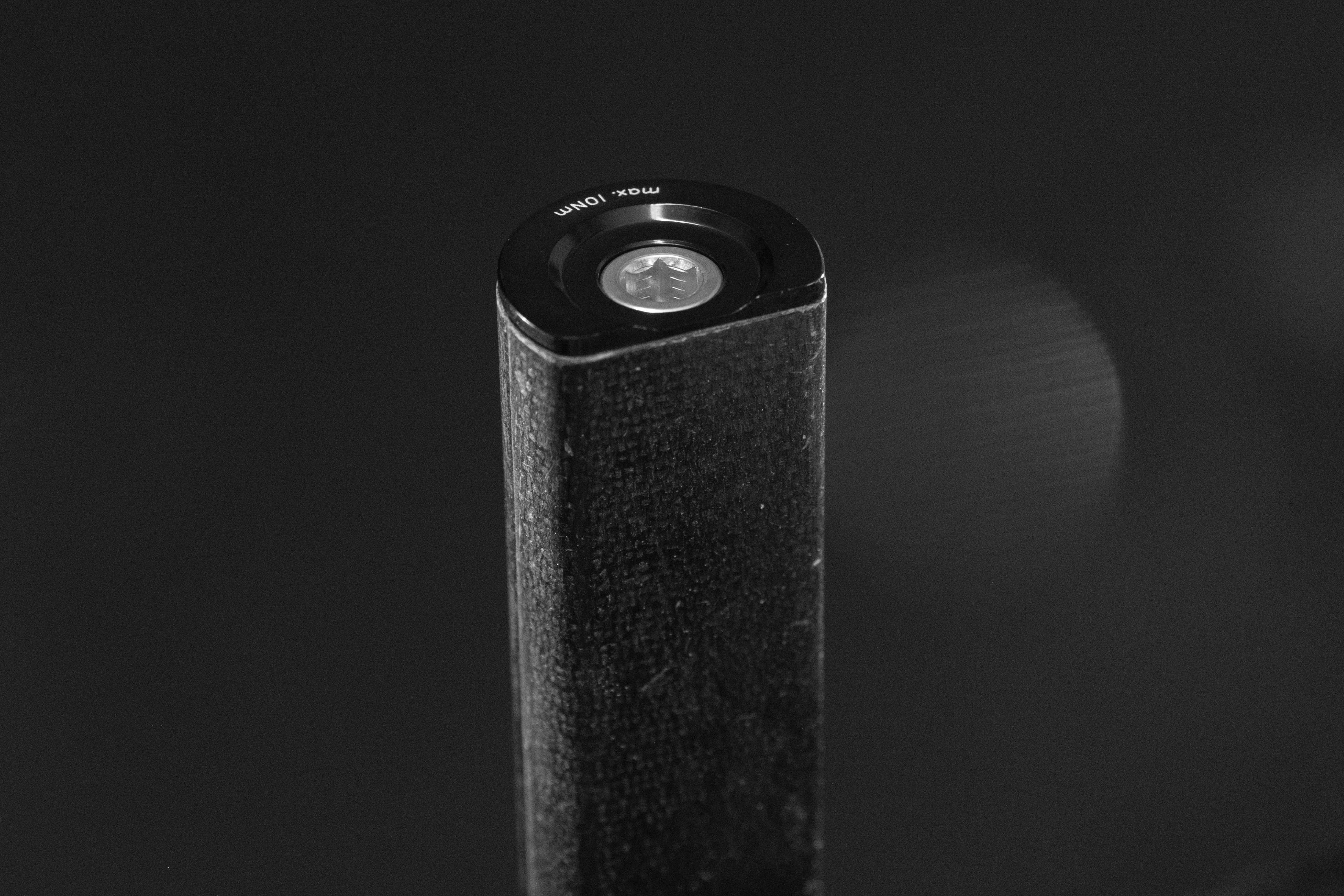 Close-up of a cylindrical black object with a rounded top, featuring a transparent circular section and text indicating 'max 10Ω'.
